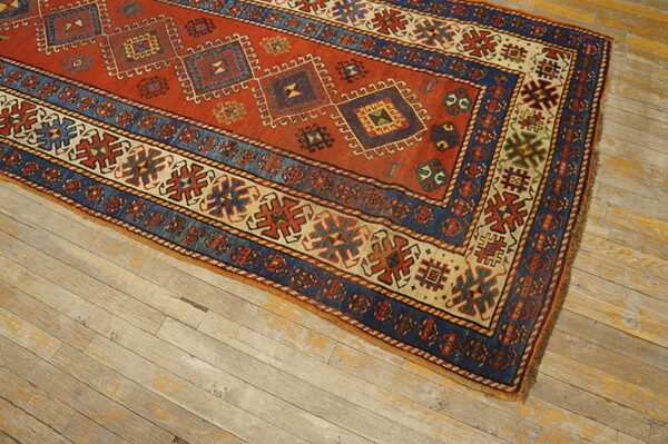 Close-up of a richly colored antique rug with geometric patterns in red and blue, resting on distressed wood floors, by rugs on net