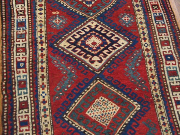 Close-up of a vibrant red and blue geometric rug pattern, featuring diamond medallions, by rugs on net. By rugs on net