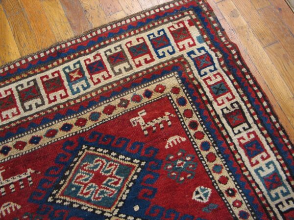 Close-up of a richly colored rug with geometric patterns in red, blue, and cream on a wooden floor by rugs on net