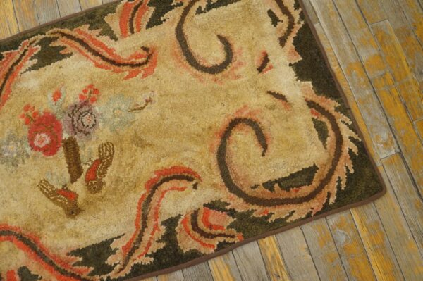 Close-up of a vintage hooked rug with beige, orange, and dark green patterns on a distressed wooden floor, by rugs on net