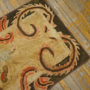 Close-up of a hooked rug with beige, brown, and red floral/scroll motifs on a dark border, resting on distressed yellow wood flooring by Rugs On Net