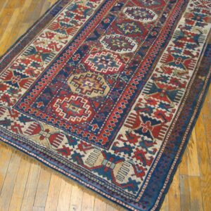 Close-up of a richly patterned, antique blue and red rug on a wooden floor by Rugs On Net. by Rugs On Net
