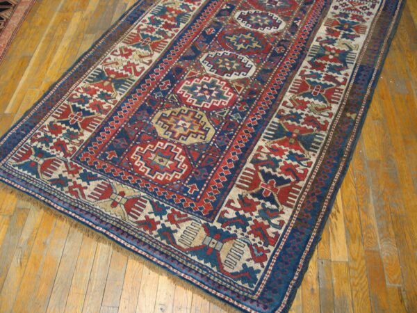Close-up of a richly patterned, antique blue and red rug on a wooden floor by rugs on net. By rugs on net