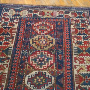 Close-up of a richly patterned antique rug featuring geometric motifs in red, blue, and cream, by Rugs On Net