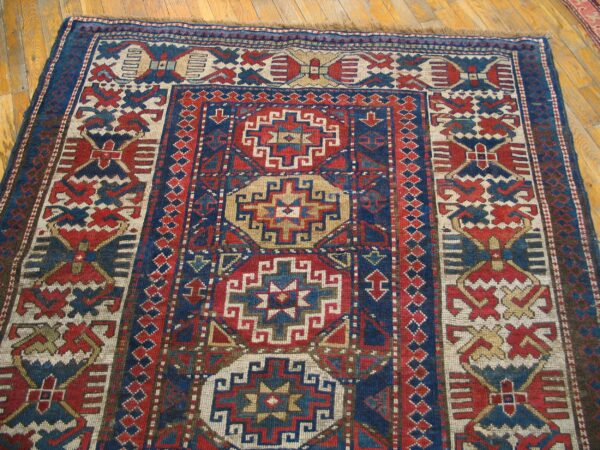 Close-up of a richly patterned antique rug featuring geometric motifs in red, blue, and cream, by rugs on net