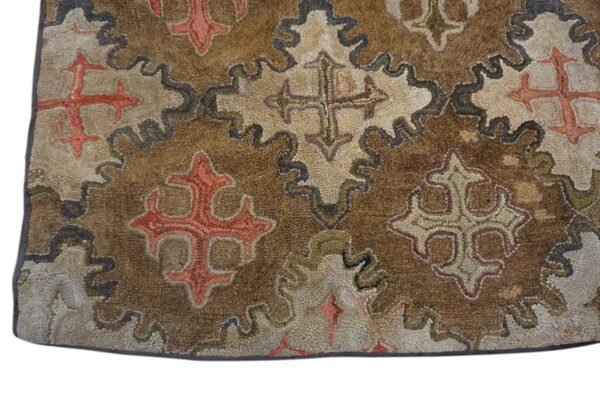 Close-up of a brown hooked rug featuring stylized cross motifs within undulating borders by rugs on net
