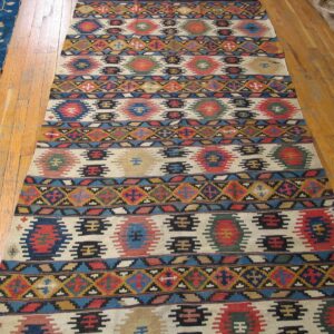 Long kilim rug with repeating geometric motifs in red, blue, and earth tones by Rugs On Net