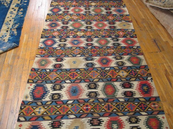 Long kilim rug with repeating geometric motifs in red, blue, and earth tones by rugs on net