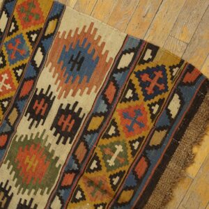 Close-up of a colorful kilim rug with geometric patterns on a wooden floor by Rugs On Net