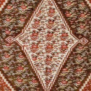 Close-up of a tribal rug with a central diamond motif in cream and red against a dark brown and rust background, by Rugs On Net