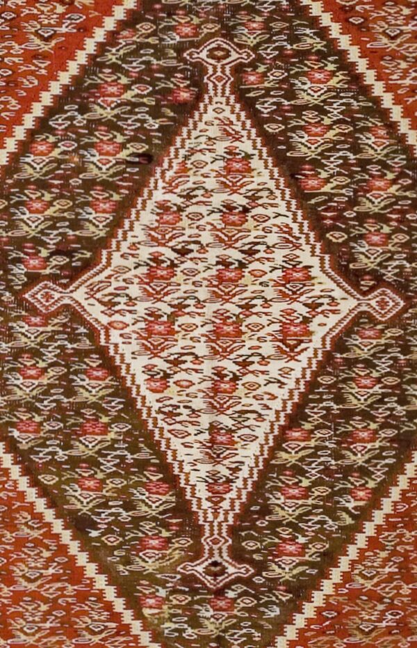 Close-up of a tribal rug with a central diamond motif in cream and red against a dark brown and rust background, by rugs on net