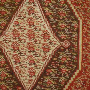 Close-up of a richly colored kilim rug featuring a central cream medallion with red floral motifs against a dark brown field, by Rugs On Net