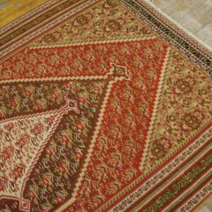 Close-up of a vibrant red and green kilim rug with geometric patterns on a light wood floor by Rugs On Net