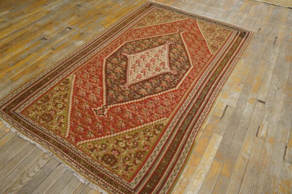 A vibrant red and green kilim rug with geometric patterns, displayed on a rustic wooden floor, by rugs on net. By rugs on net