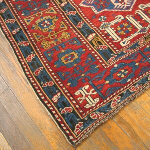 Close-up corner view of a vibrant red and blue antique rug on a wooden floor by Rugs On Net