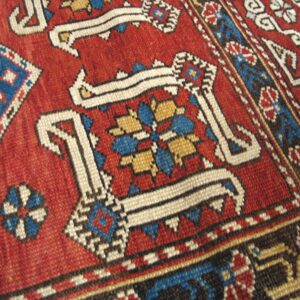 Close-up of a vibrant red and blue geometric pattern on an antique rug by Rugs On Net