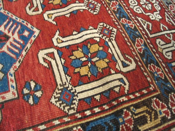Close-up of a vibrant red and blue geometric pattern on an antique rug by rugs on net