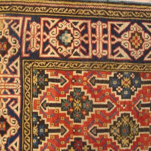 Detail of a richly colored rug with geometric patterns in red, blue, and cream, by Rugs On Net