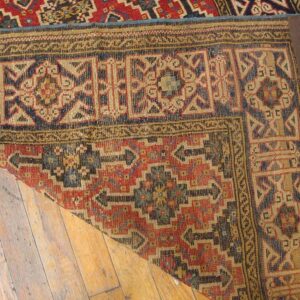 Close-up corner of a geometric rug showing red, blue, and tan patterns, by Rugs On Net
