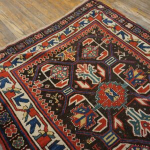 Close-up of a richly patterned antique rug featuring geometric motifs in red, blue, and cream on a dark field, by Rugs On Net