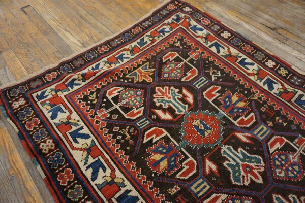 Close-up of a richly patterned antique rug featuring geometric motifs in red, blue, and cream on a dark field, by rugs on net
