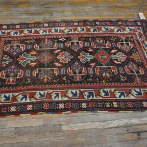 A dark-field geometric rug with red and blue accents on a rustic wooden floor by Rugs On Net