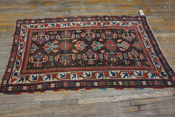 A dark-field geometric rug with red and blue accents on a rustic wooden floor by rugs on net