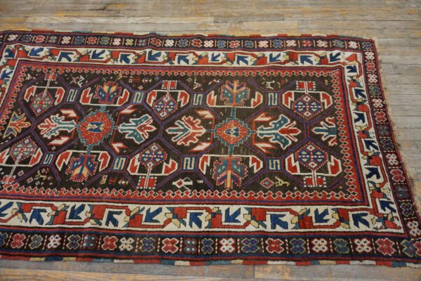 A close-up view of a richly patterned antique rug featuring geometric motifs in dark brown, red, and blue, by rugs on net. By rugs on net