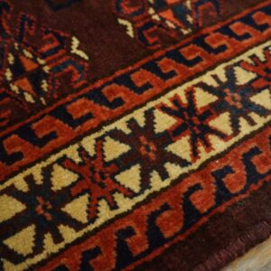 Close-up of the geometric border pattern on a dark red rug by Rugs On Net