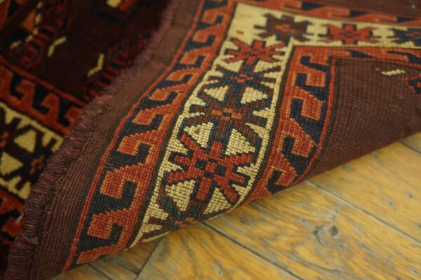 Close-up of the edge and border pattern of a deep red and beige tribal rug by rugs on net. By rugs on net