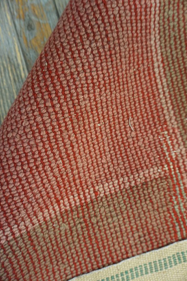 Faded pink rug with green border.