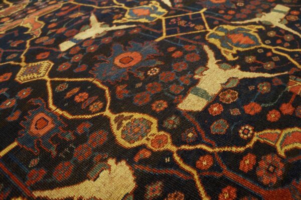 Close-up of a dark field rug with geometric patterns and stylized animal figures in red, blue, and cream, by rugs on net