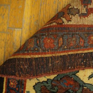 Close-up showing the weave and border detail of the Persian Rug by Rugs On Net, partially rolled back over a wooden floor by Rugs On Net. by Rugs On Net