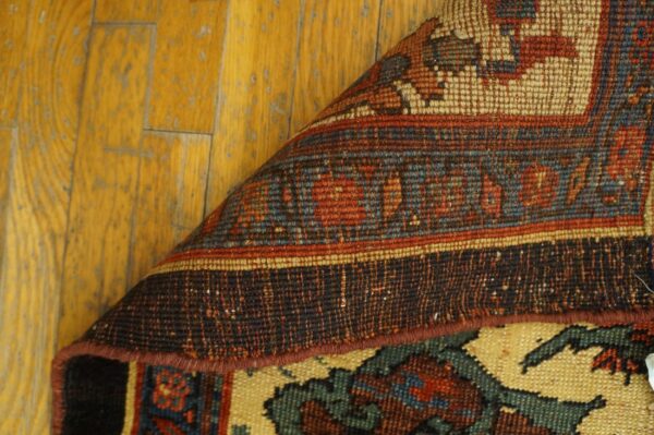 Close-up showing the weave and border detail of the persian rug by rugs on net, partially rolled back over a wooden floor by rugs on net. By rugs on net