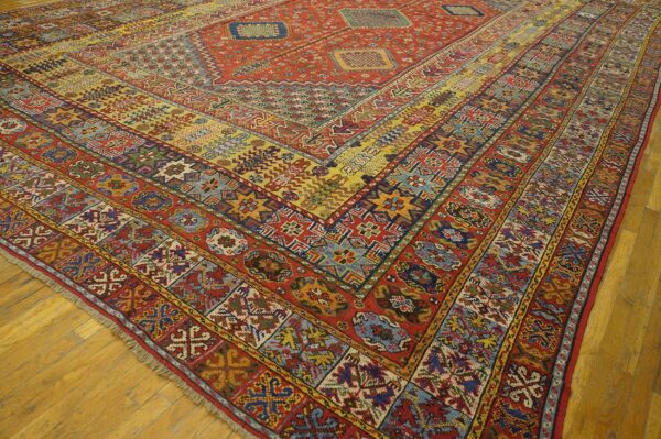 Close-up view of a richly patterned, antique rug with dominant red and yellow tones, showcasing intricate geometric borders by rugs on net. By rugs on net