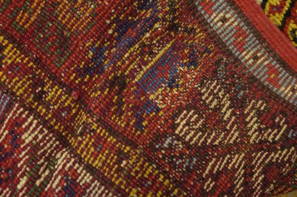 Close-up texture of a richly colored, woven rug with diagonal patterns in red, yellow, and blue by rugs on net. By rugs on net