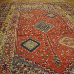 A vibrant, antique rug with a dominant red field and geometric medallions, featuring multi-colored striped borders, by Rugs On Net