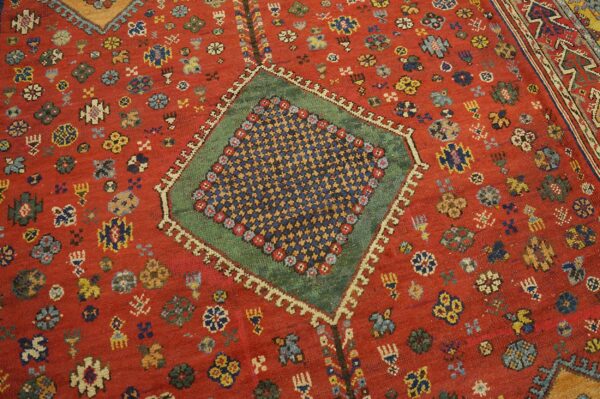 Close-up of a red field rug with scattered floral motifs and a central green-bordered medallion, by rugs on net