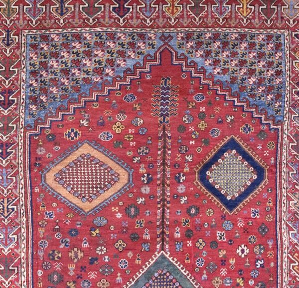Close-up of a prayer rug with a red field and geometric motifs by rugs on net