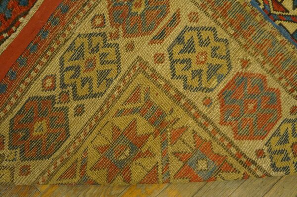 Close-up detail of a woven rug corner with geometric patterns in gold, red, and blue by rugs on net
