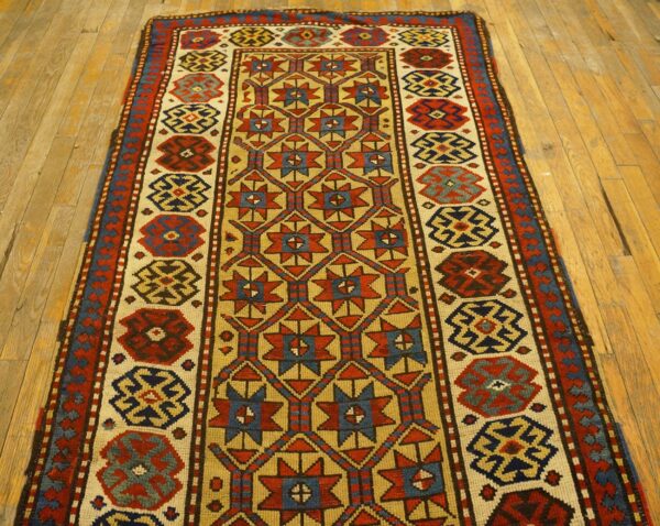 A long runner rug with geometric patterns in red, blue, and gold on a light background, laid on wooden floorboards, by rugs on net