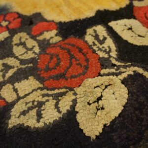 Close-up of a hooked rug featuring red roses and cream leaves on a dark background, by Rugs On Net