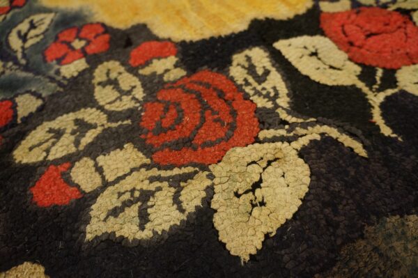 Close-up of a hooked rug featuring red roses and cream leaves on a dark background, by rugs on net