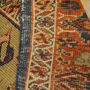 Close-up texture of the antique rug border featuring geometric patterns in red, blue, and beige tones by Rugs On Net. by Rugs On Net