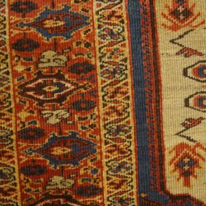Close-up detail of a traditional rug border featuring red, blue, and gold geometric patterns by Rugs On Net. by Rugs On Net