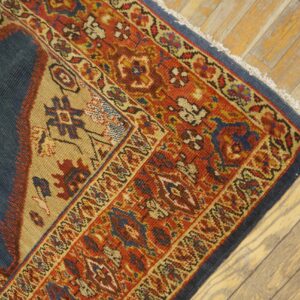 Close-up corner detail of an antique rug with rich red, blue, and tan geometric patterns resting on distressed wooden floors by Rugs On Net. by Rugs On Net
