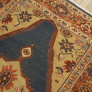 Close-up of a traditional rug showing dark blue field, tan accents, and intricate red border designs by Rugs On Net. by Rugs On Net