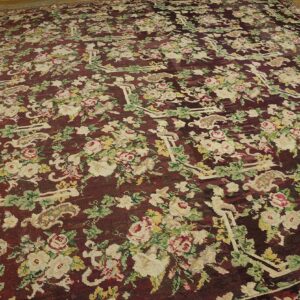 Close-up of a dark burgundy rug featuring an all-over floral pattern with cream and pink roses and green foliage, by Rugs On Net