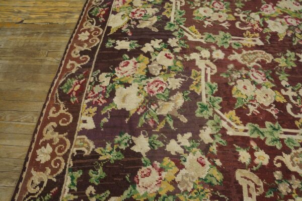 Close-up of a dark aubergine floral needlepoint rug on wood flooring by rugs on net