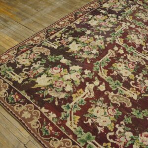 Close-up of a richly colored floral rug with a dark red field and cream roses, by Rugs On Net